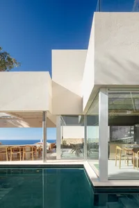Modern residential home with concrete exterior, glass walls, and a swimming pool.