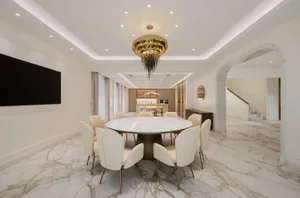 Modern residential interior with marble flooring and furniture, featuring a round dining table and chairs, a kitchen in the b