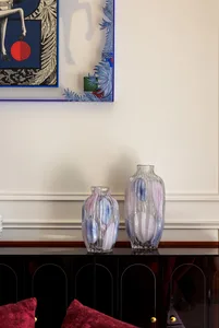 Two glass vases with blue and white patterns on a black cabinet.