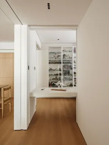 A minimalist display cabinet with glass shelves showcasing various collectibles and artifacts.