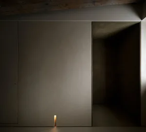 An interior space with a minimalist design featuring a concrete wall and doorway.