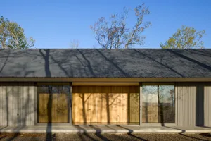 A minimalist modern building exterior with metal cladding and large sliding glass doors.