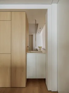 Modern minimalist kitchen with white laminate countertops, wooden cabinets, and a metal pipe structure