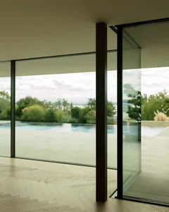 A modern glass window overlooking a serene outdoor space and pool, framed by minimal interior design.