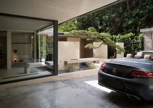 Modern home with concrete exterior and porch surrounded by trees.