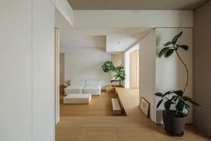 Modern interior with light wood flooring, white furniture, and green plants