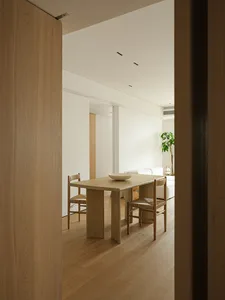 Minimalist-style living room with wood furniture, white walls, and natural light.