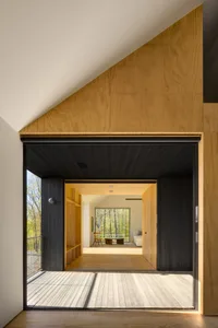 Modern minimalist residential interior featuring wood, glass, and a large window view.