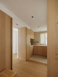 Modern minimalist residential kitchen with wooden cabinets and a light-colored countertop.