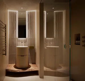 A modern bathroom featuring neutral-toned tiles, a rounded sink, and minimalistic design elements.