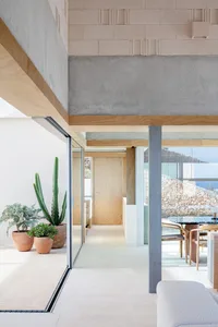 A modern residential interior featuring concrete walls and floors, glass doors, and minimalistic furniture.