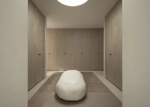 A minimalist bedroom with neutral tones and a sculptural white bench.