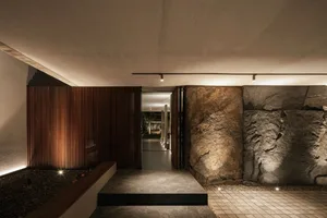 Modern, minimalist architectural entrance featuring a combination of concrete, wood, and stone elements.