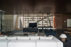 A modern, minimalist residential interior featuring concrete and metal materials, with a focus on open space and natural ligh