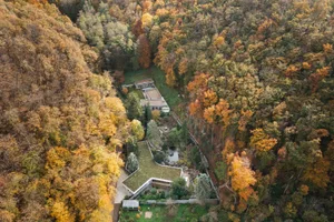 Aerial view of modern architecture nestled within an autumn forest.