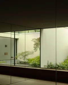 Modern room with glass wall and concrete pavement showcasing framed garden view