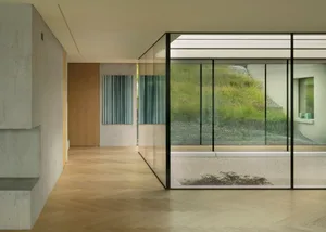 Modern living room featuring concrete walls, glass windows, and wooden flooring