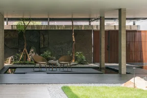Modern living room with concrete walls, glass doors, and wooden furniture