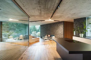 Modern living room with concrete walls, wooden floors, and stone accents