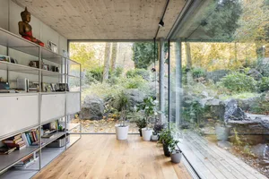 A modern living space featuring wooden flooring near a natural setting.
