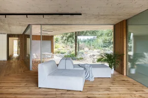 A modern living space with a glass wall and wooden flooring.