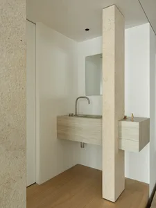 A modern minimalist bathroom with a concrete sink and mirror.