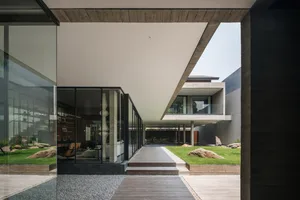 Modern residential exterior featuring glass walls and concrete structures.