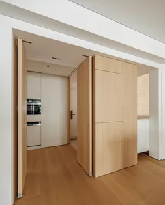 A modern residential kitchen featuring natural wood cabinets and white surfaces.