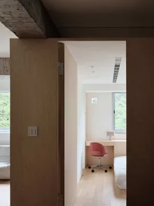 A minimalist bedroom featuring solid wood furniture and natural light from a large window.