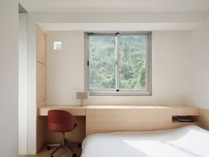 A minimalist bedroom featuring wood, glass, and metal materials with a view of greenery through the window.