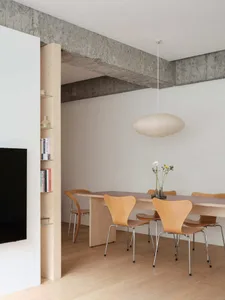 Modern minimalist dining area with a concrete ceiling, wooden table, and chairs