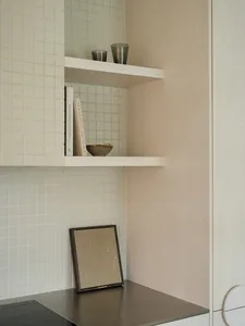 A modern kitchen with a wooden shelf and a tiled wall.