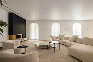 Modern living room with white fabric sofa, arched windows, and marble coffee tables