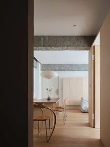 A modern living room with wooden floors, concrete accents, and a single wooden chair.