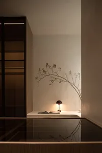 A minimalist bedroom with a wooden table, a lamp, and an open book.