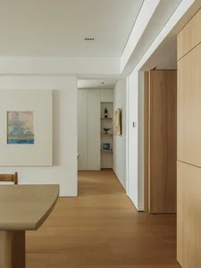 Minimalist dining room with a wooden floor and table, featuring a simple and clean design aesthetic.
