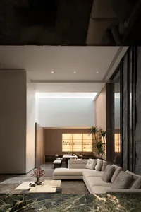 Modern minimalist living room with a concrete wall and marble accents.