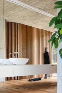 A minimalist bathroom featuring wooden wall panels and a white sink