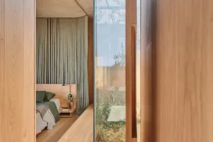 A minimalist bedroom featuring wooden furniture and green curtains.