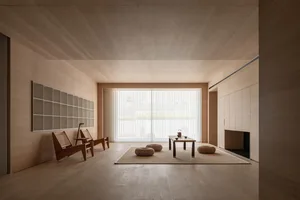 Modern minimalist living room with wood and plaster walls, concrete flooring, and adjustable lighting fixtures.