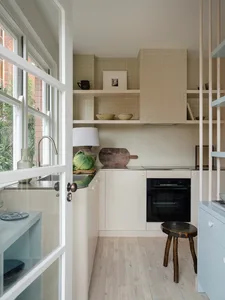 A minimalist residential kitchen with wood finishes and white cabinets.
