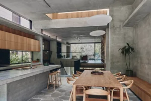 Interior of a modern kitchen with concrete walls and a wooden dining table.