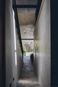 A narrow concrete hallway with stone flooring and a view of the outdoors.