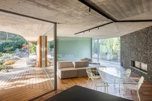 Modern living room featuring a concrete ceiling and glass walls.