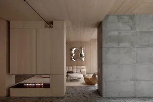 A modern lobby featuring a concrete seating area with wooden accents and minimalist decor.