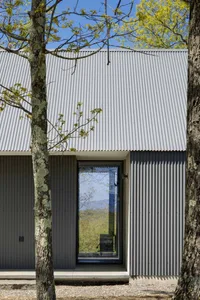 Modern house exterior with corrugated metal siding and large window.
