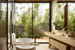 Modern minimalist bathroom with concrete walls, wood accents, and a serene garden view through large windows.