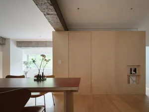 簡約住宅餐廳區，木質餐桌、餐椅與花瓶擺放在混凝土樑前
