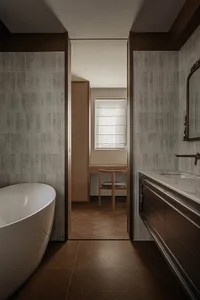 A modern bathroom featuring concrete tiled walls, wooden flooring, and a freestanding bathtub. A vanity with a marble top and