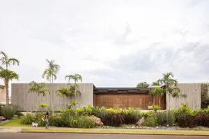 A modern house with concrete exterior surrounded by lush greenery.